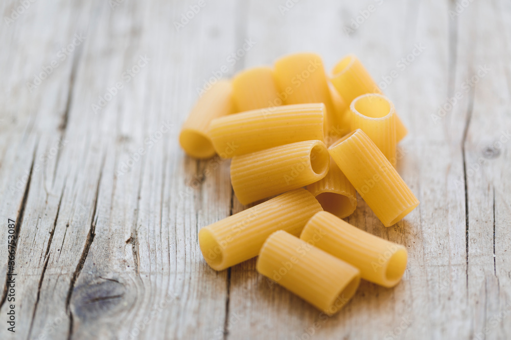 a lot of different kinds of egg noodles and yellow pasta on wooden background a lot of different kinds of egg noodles and yellow pasta on wooden background