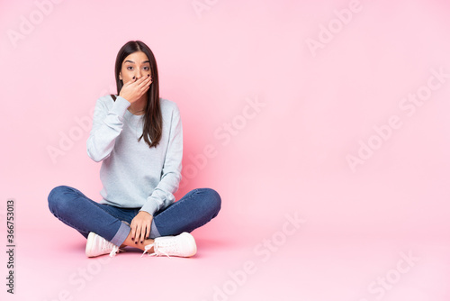 Young caucasian woman isolated on pink background covering mouth with hands