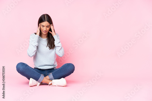 Young caucasian woman isolated on pink background with headache