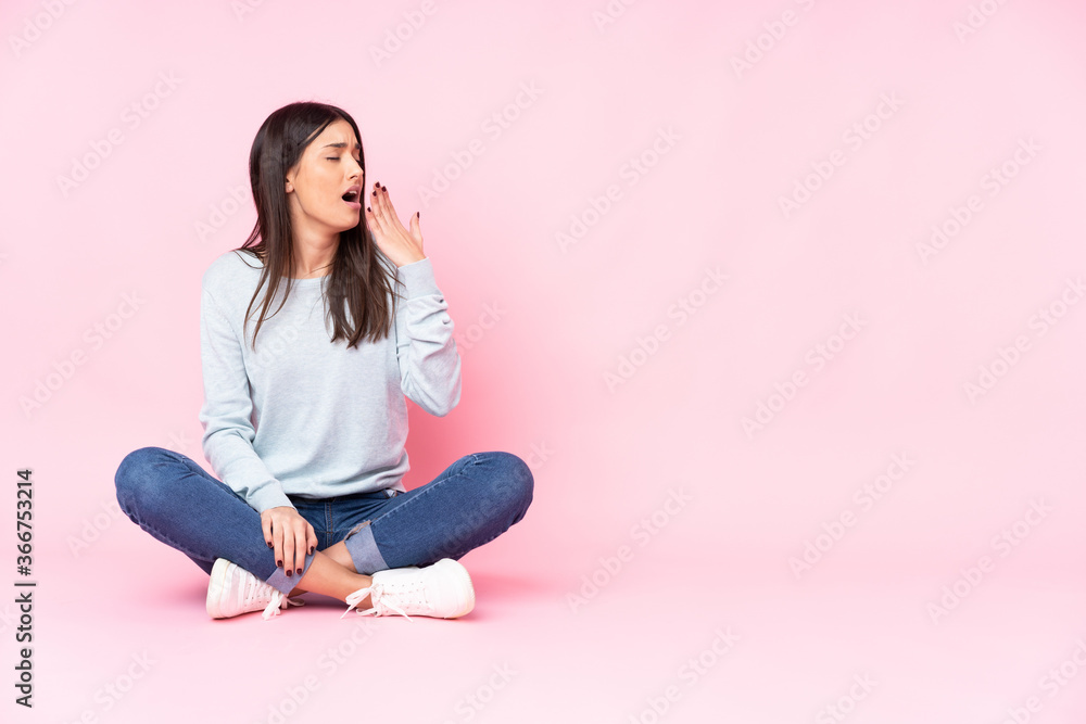 Young caucasian woman isolated on pink background yawning and covering wide open mouth with hand