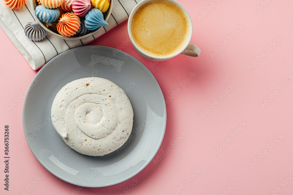 White meringue cookie on pink background with colorful mini meringues White meringue cookie on pink background with colorful mini meringues