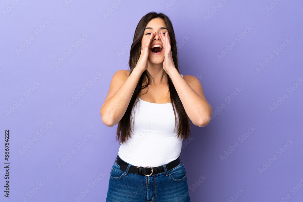 Teenager Brazilian girl over isolated purple background shouting and announcing something