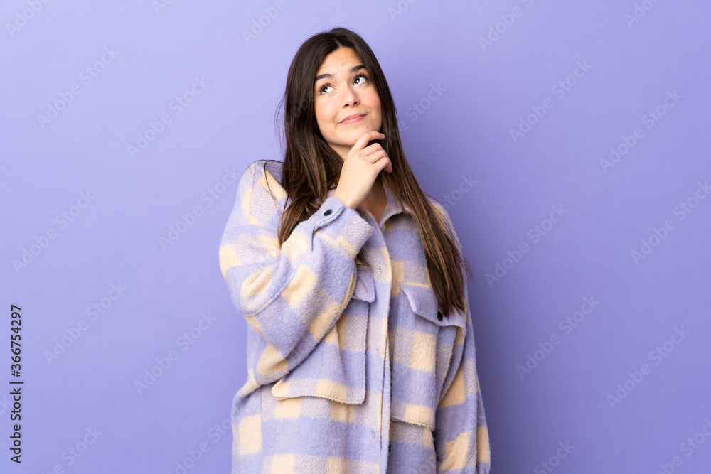 Teenager Brazilian girl over isolated purple background and looking up Teenager Brazilian girl over isolated purple background and looking up