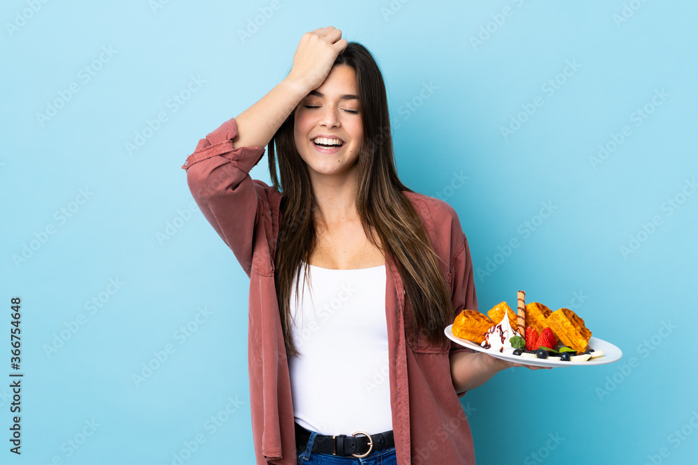 Teenager Brazilian girl holding waffles over isolated blue background has realized something and intending the solution Teenager Brazilian girl holding waffles over isolated blue background has realized something and intending the solution