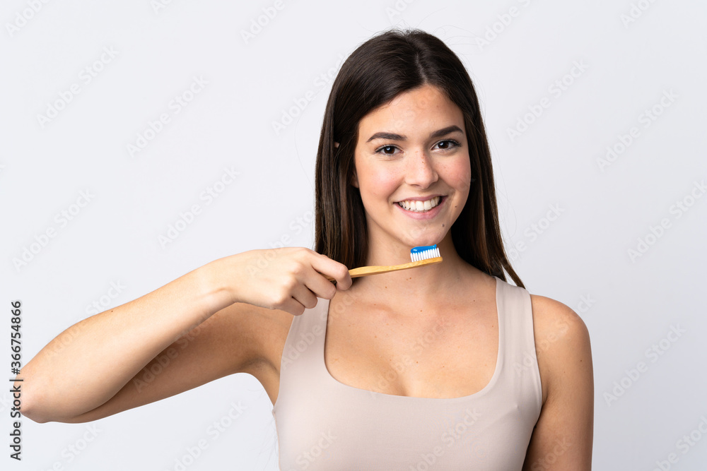 Teenager Brazilian girl brushing her teeth over isolated white background Teenager Brazilian girl brushing her teeth over isolated white background