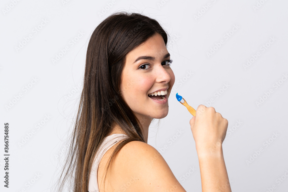 Teenager Brazilian girl brushing her teeth over isolated white background Teenager Brazilian girl brushing her teeth over isolated white background