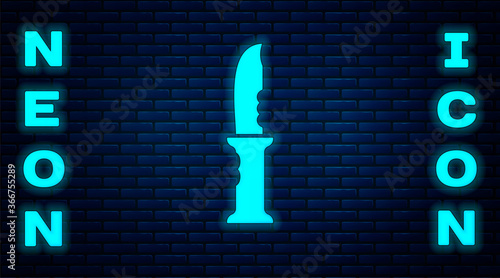 Glowing neon Military knife icon isolated on brick wall background. Vector.