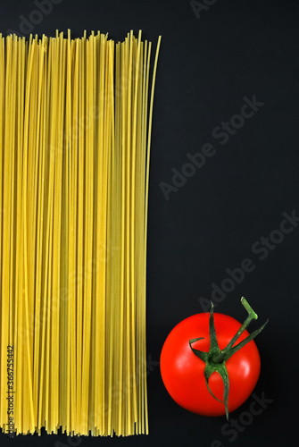 Spaghetti and red tomato on a black background.
