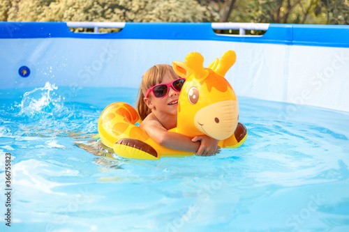 A child swims in a swimming pool with an inflatable toy. Summer vacation