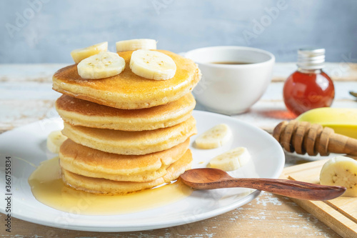 Pancakes topped with honey and bananas on the table