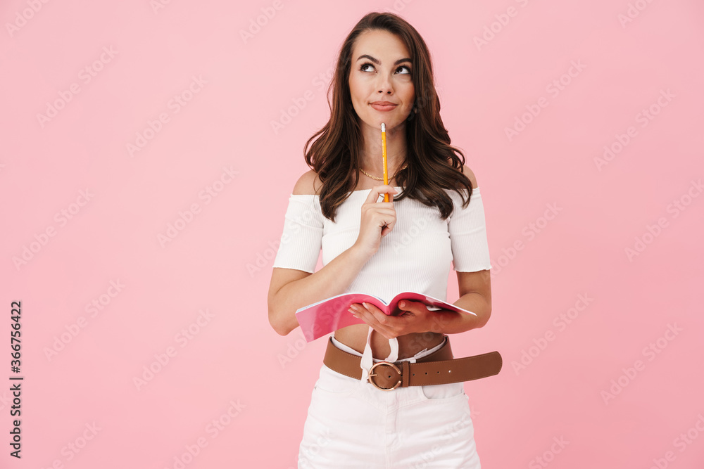 Image of pleased young woman holding exercise book and thinking Image of pleased young woman holding exercise book and thinking