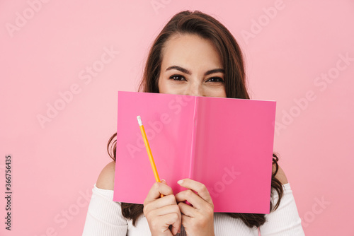 Image of joyful young woman holding exercise book and laughing