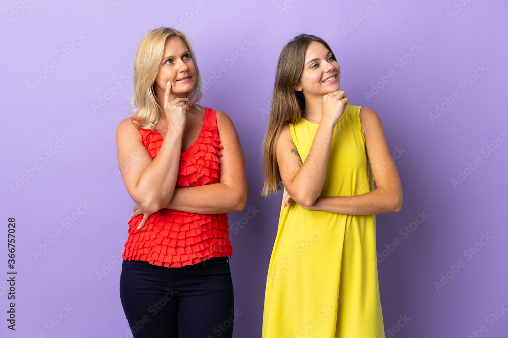Mom and daughter isolated on purple background thinking an idea while looking up Mom and daughter isolated on purple background thinking an idea while looking up