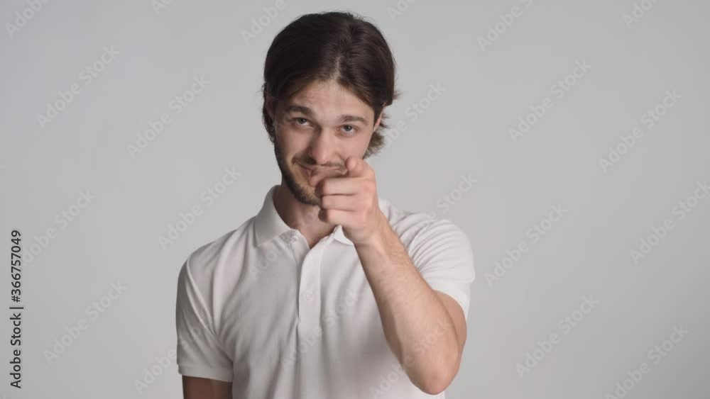 Attractive stylish guy confidently showing you gesture on camera over gray background. Pointing index finger in camera Attractive stylish guy confidently showing you gesture on camera over gray background. Pointing index finger in camera