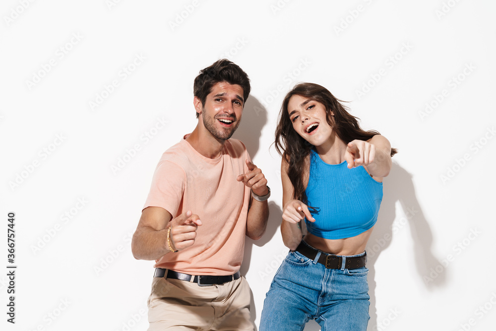 Fototapeta premium Image of delighted couple smiling and pointing fingers upward