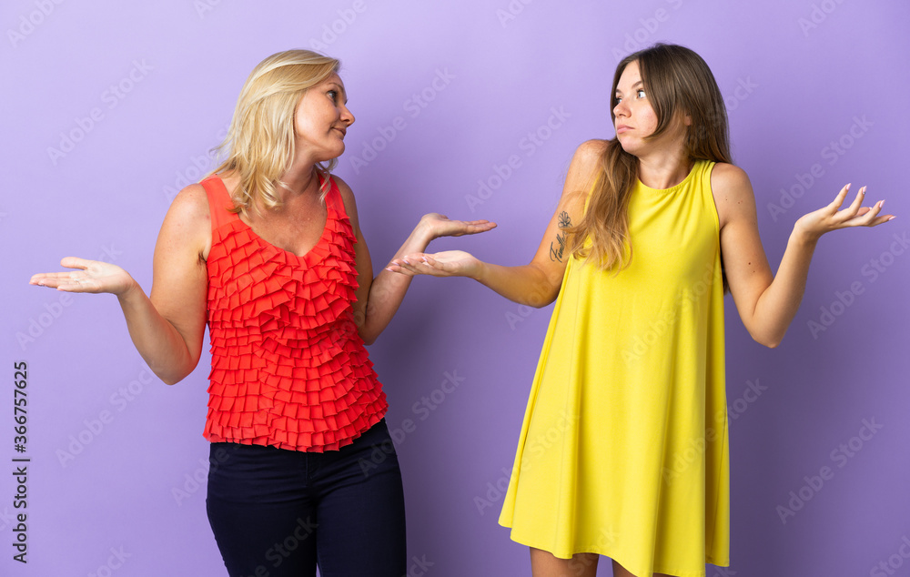 Mom and daughter isolated on purple background making unimportant gesture while lifting the shoulders Mom and daughter isolated on purple background making unimportant gesture while lifting the shoulders