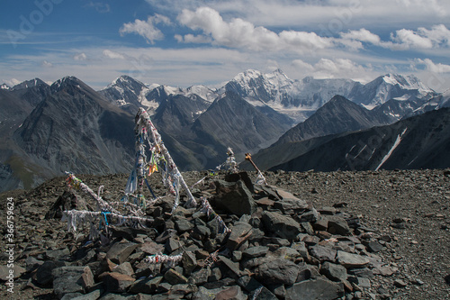 Ritual colored strips of fabric on a mountain pass against the background of Mount Belukha. Gorny Altai, Russia.