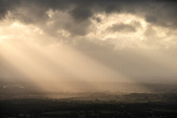 Papier peint photo Pantone 2025 Mocha Mousse Beautiful landscape image of sunset over English countryside with sun beams lighting up the fields below  © veneratio