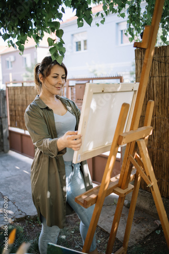 Photo Artist placing canvas on wooden tripod in outdoor workshop