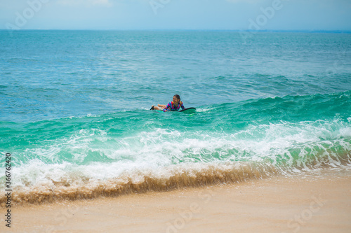 Sexy slim girl riding on surf board in the ocean. Healthy active lifestyle in summer vocation.