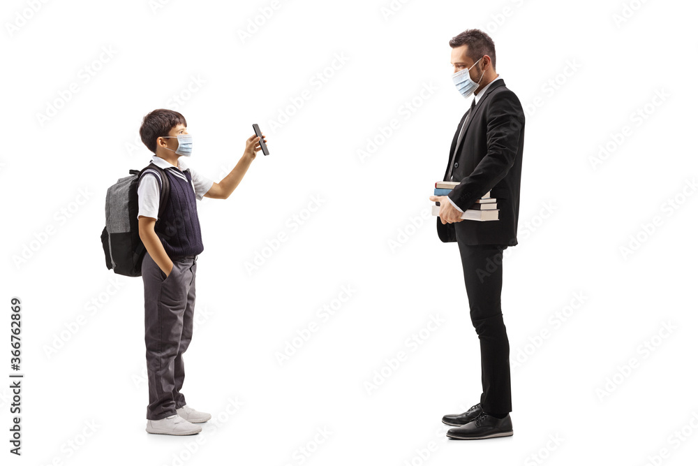 Schoolboy wearing a protective face mask and showing a mobile phone to a teacher Schoolboy wearing a protective face mask and showing a mobile phone to a teacher