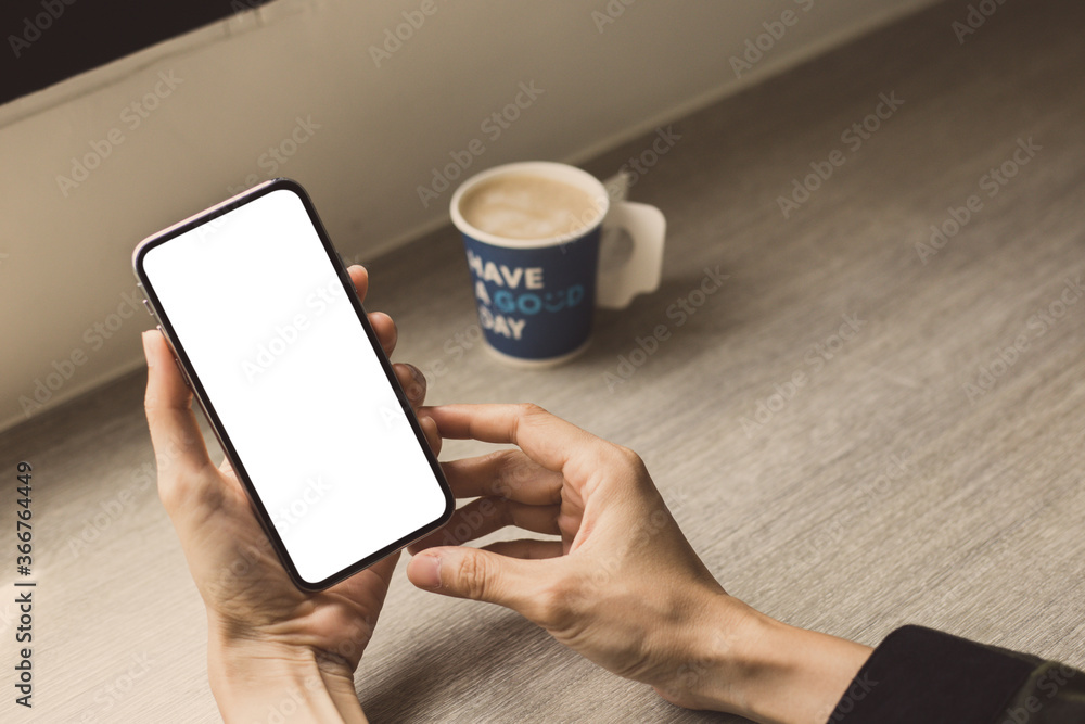 cell phone mockup image blank white screen.woman hand holding texting using mobile on desk at coffee shop.background empty space for advertise.work people contact marketing business,technology j