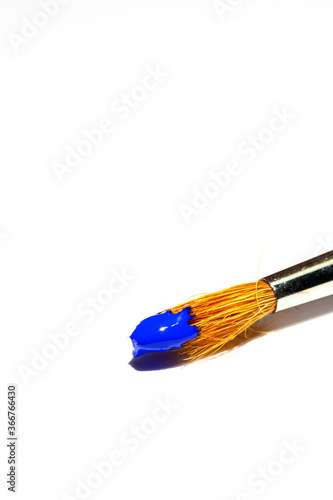 Artists paint brush loaded with blue paint isolated on a white background