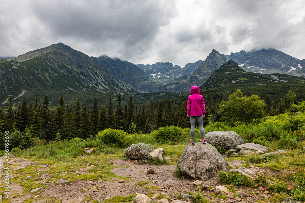 Hooded woman looking at the Tatra mountain panorama in the rain