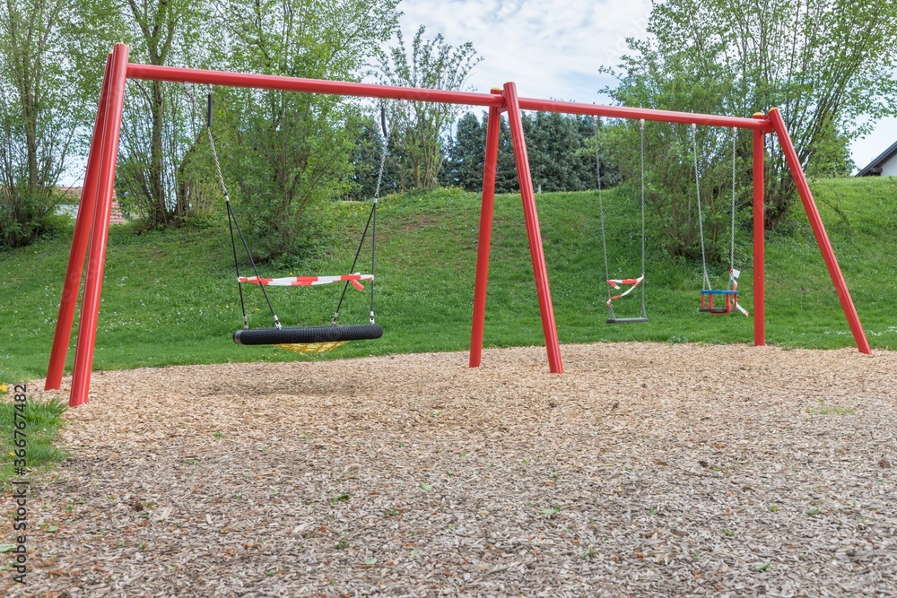 Fototapeta premium Corona virus quarantine lockdown prohibit playground swings. Closure by barrier tape. Covid-19 safety prevention action containing pandemic spread risk. Coronavirus restriction by law regulations