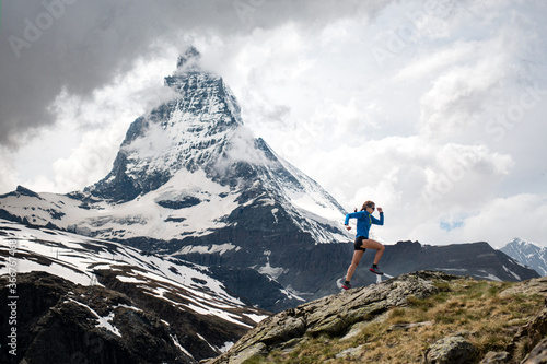 Trail runner woman running with scenic view of Matterhorn mountain in the Swiss Alps
