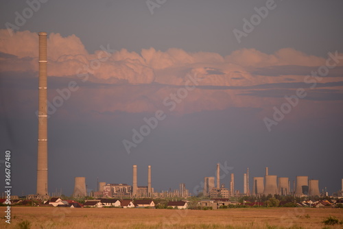 oil refinery seen on the horizon on the wheat field at sunset