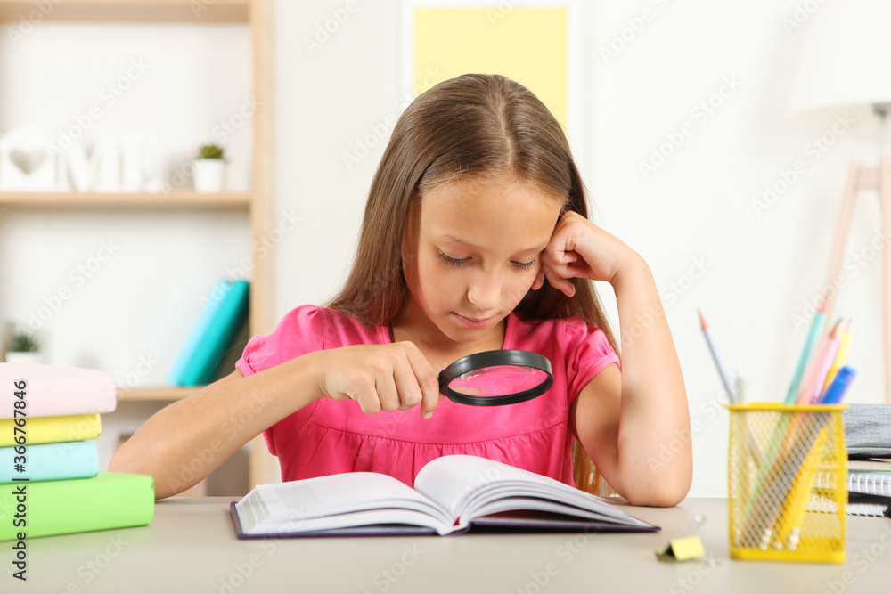 Cute little girl with poor eyesight reads with a magnifying glass
Cute little girl with poor eyesight reads with a magnifying glass