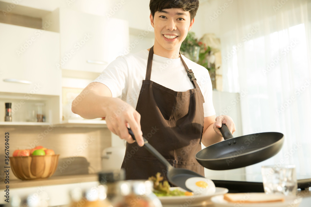 Young man is cooking sunny side up egg and salad for breakfast Young man is cooking sunny side up egg and salad for breakfast