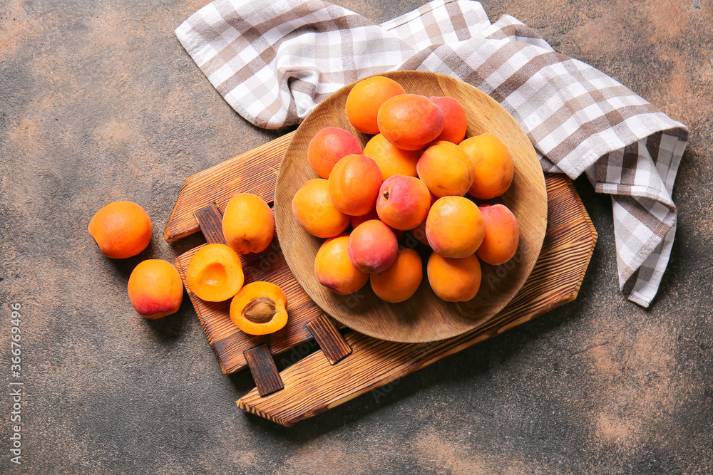 Plate with tasty ripe apricots on grey background
