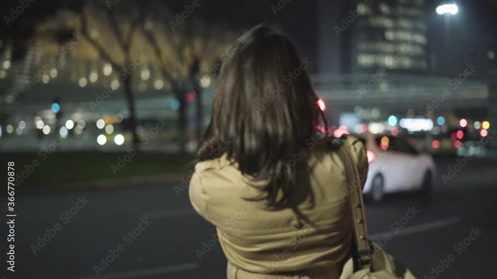 Joyful young woman in overcoat using smartphone for video call, raising hands with phone, talking to boyfriend, turning around on city street. Night, medium shot. Communication concept Joyful young woman in overcoat using smartphone for video call, raising hands with phone, talking to boyfriend, turning around on city street. Night, medium shot. Communication concept
