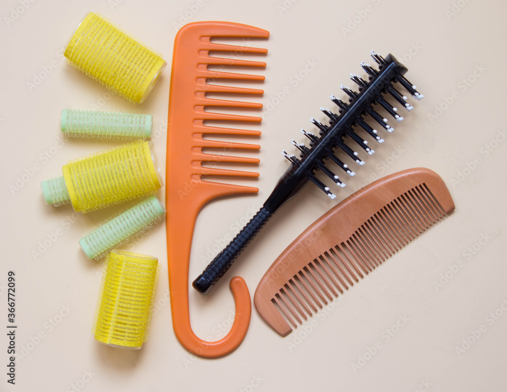 Green yellow curlers, combs, hair brush. Hair care concept. Pastel background. Top view Green yellow curlers, combs, hair brush. Hair care concept. Pastel background. Top view