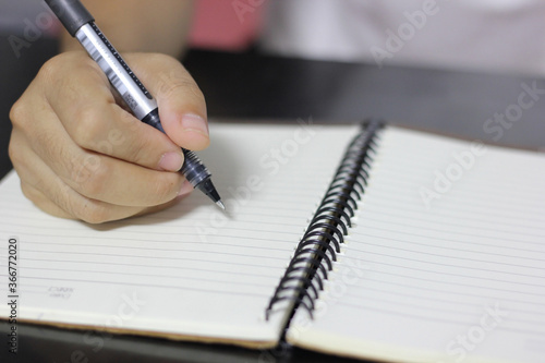 Closeup of pen in woman's hand writing on notebook for some idea on a book, lecturing, studying, signing, education, school, institute, university, office and working concept.  © Muanpare