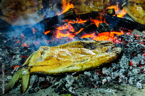Fish steaks are grilled. Close-up of pieces of fish. Round grill bowl, round roaster with a fire in the center