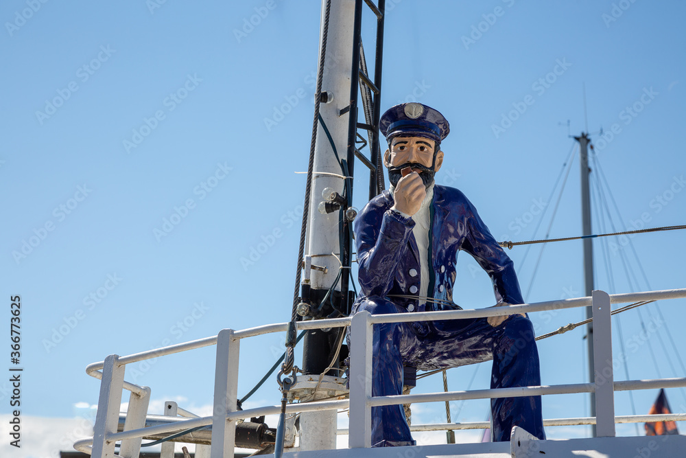 Ein Seemann in blauer Kleidung und mit einer Pfeiffe sitzt auf einem Schiff Ein Seemann in blauer Kleidung und mit einer Pfeiffe sitzt auf einem Schiff