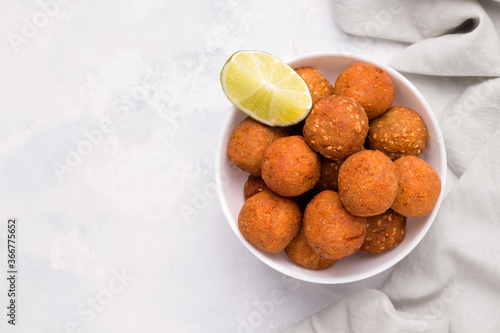 A Middle Eastern vegan dish, falafel. Fried ready-made chickpea balls in bowl with lime on white plate photo