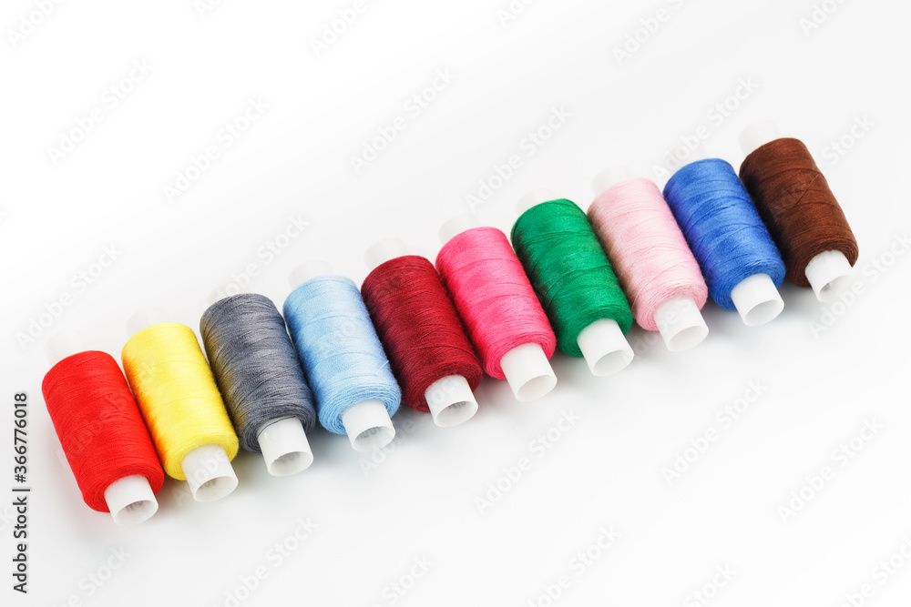 Sewing threads of different colors on reels on a white background. Free space, close-up. Isolate Sewing threads of different colors on reels on a white background. Free space, close-up. Isolate