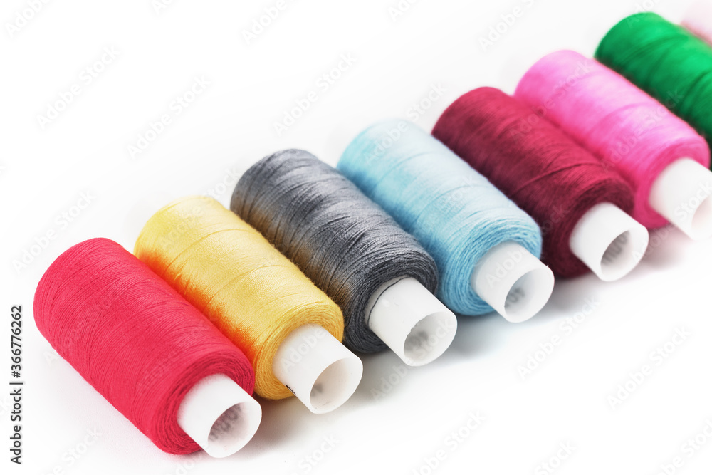 Sewing threads of different colors on reels on a white background. Free space, close-up. Isolate Sewing threads of different colors on reels on a white background. Free space, close-up. Isolate
