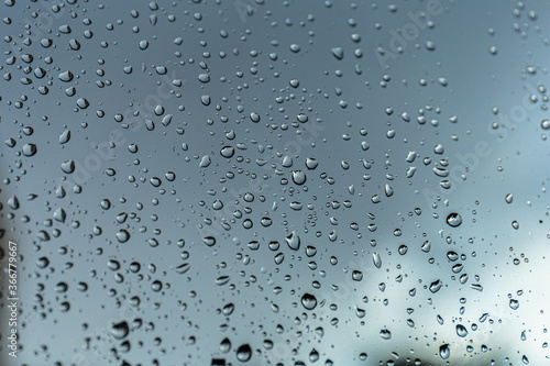 Rain drops on window glass, natural background of rainy season.
