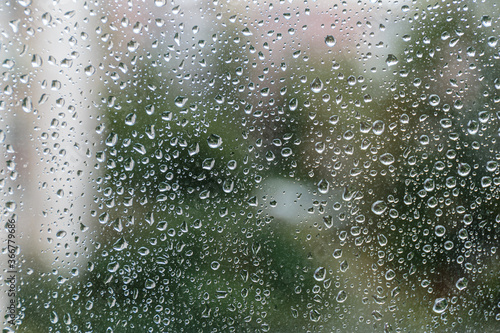 Rain drops on window glass, natural background of rainy season.