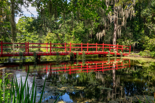 A beautiful red foot bridge with reflection crosses a pond on a plantation near Charleston, South Carolina.