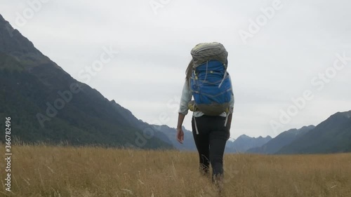 Woman walking in Beautiful grass Field with Mountain in Background New Zealand