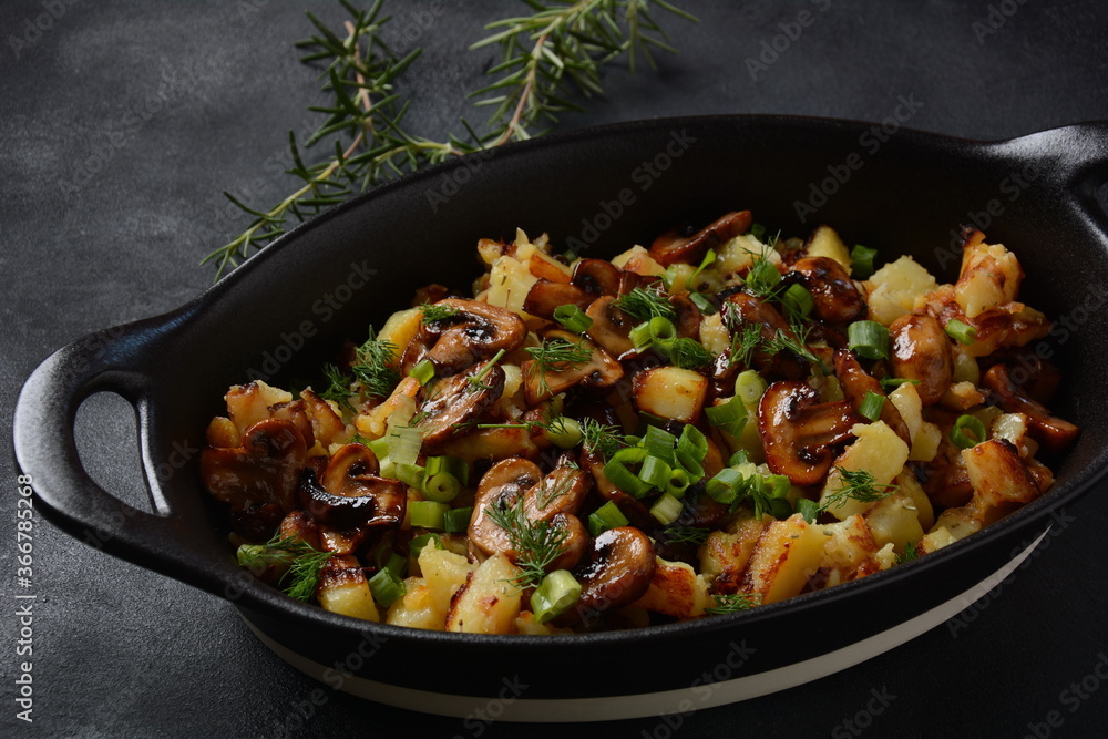 Fried potatoes with mushrooms in a plate/and frying bowl with herbs. Fried potatoes with mushrooms in a plate/and frying bowl with herbs.