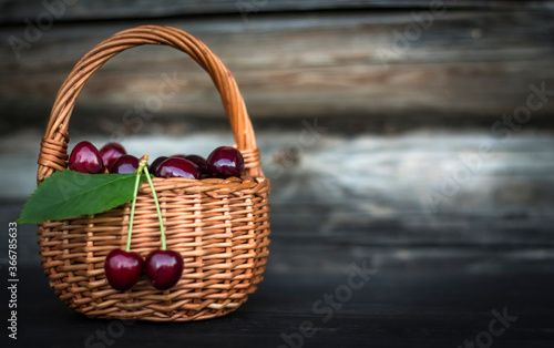 cherries in a basket on a dark wooden background close up with a copy of the space
