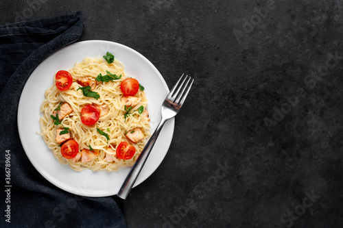  pasta with salmon and tomatoes on a stone background with copy space for your text