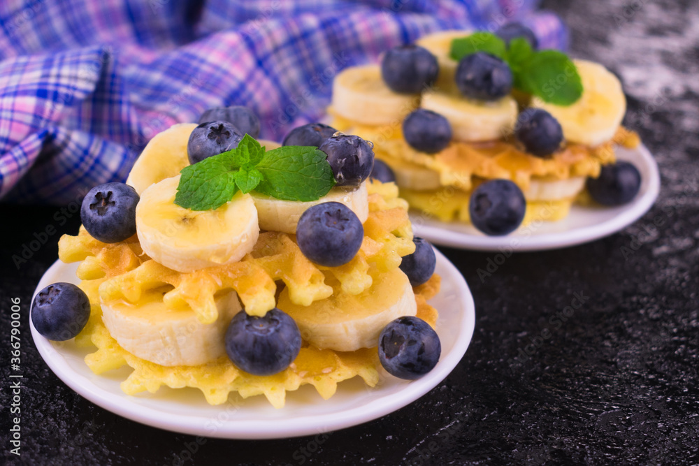 Two portions of waffles with berries and banana on a white plate.
Close-up. Delicious breakfast. Two portions of waffles with berries and banana on a white plate.
Close-up. Delicious breakfast.